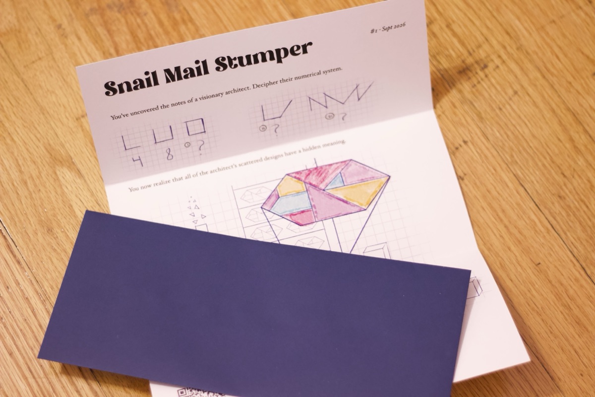 a trifold puzzle lays open on a desk, with an envelope laying on top of it.